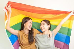 LGBT group. Good looking lesbian couples smile brightly cover rainbow flags. Asian young couple hugging each other happily, lover in love, bisexualities, homosexuality, liberty, expression, happy life photo