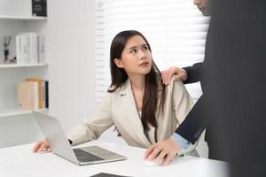 businessman sexually harassed a female colleague by touch her shoulder. Sexual harassment in office. Women feel anxious and stressed from being harassed. molest, assault, inappropriate, discrimination photo