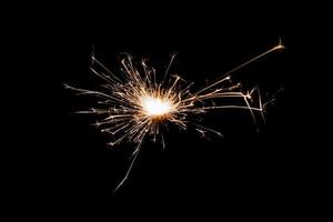 Burning sparkler isolated on black background. Fireworks theme. Light effect and texture. photo