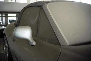 Closeup side mirror of the car covered by full of dust abandoned in the parking lot photo