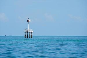 The concrete structure of lighthouse in the sea with horizontal line and blue sky in background photo