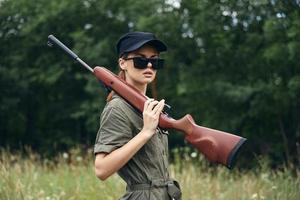 Woman on outdoor holding a weapon on his shoulder sunglasses green jumpsuit photo