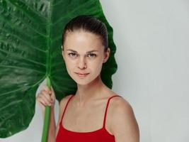 pretty woman in red swimsuit holding palm leaf in her hands charming look photo