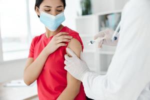 doctor holding a syringe injected into the shoulder of a woman patient covid vaccination photo