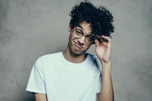 man with curly hair wearing glasses emotions white t-shirt studio photo