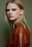 Headshot portrait of stylish confident professional blonde model looks at camera. Closeup shot in studio on over olive green background photo