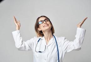 hembra enfermero en un médico vestido gesticulando con su manos en un ligero antecedentes foto