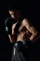 Boxer en negro guantes en un oscuro antecedentes inflado torso foto