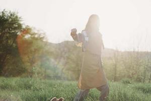 A woman running through a field on a summer day with long flowing hair in the rays of the setting sun. The concept of freedom and harmony with nature photo