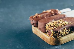 Eskimo ice cream in chocolate glaze on wooden board on stone background. Yummy sweet food photo
