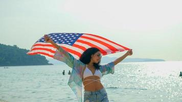 young women hold American flags on the beach and the sea on their summer vacation and they smile and enjoy their vacation. photo