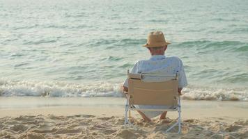 elderly men sit at the beach watching the sun and the sea on their summer vacation and they smile and enjoy their vacation. photo