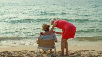 An elderly couple hugs their shoulders at the beach on their summer vacation and they smile and enjoy their vacation. photo