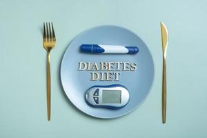 Diabetes Diet text. Glucometer and fork in plate on colored background flat lay, top view. Diet for Diabetics Minimal concept photo
