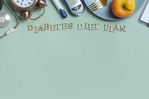 Diabetes Diet Plan text. Stethoscope, glucometer and plate with copy space on colored background photo