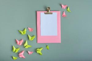 Massage board mockup with paper butterflies green and pink color flat lay on a colored background photo