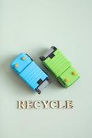 Two toy garbage trucks and recycle text on a green background photo