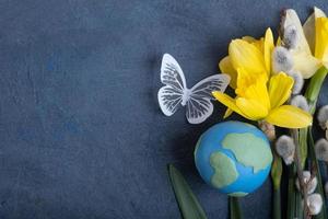 Globe, flowers and butterfly with copy space. Happy Earth day concept flat lay, top view. photo