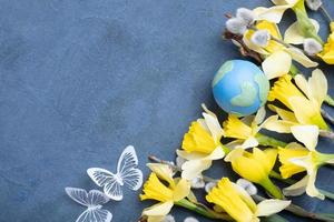 Globe, flowers and butterfly with copy space. Happy Earth day concept flat lay, top view. photo