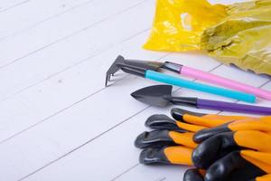 Gardening tools with gloves and soil on wooden table. Home gardening concept photo