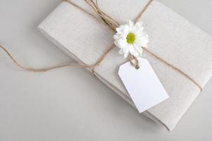 Empty price tag on white fabric, gift linen fabric with a tag on a white background with a flower photo