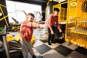 Two brothers riding with modern video game console by sensor at kids play center. photo