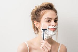 Woman shaving face with razor photo