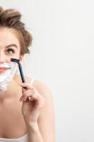 Woman shaving face with razor photo