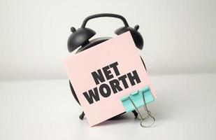 alarm clock with pink sticker with the text net worth photo