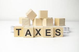 wooden cube block with taxes business word on table background. photo