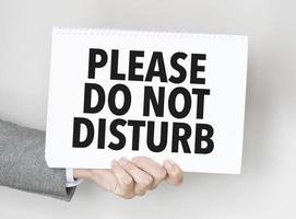 man's hand holding paper sheet with please do not disturb words photo