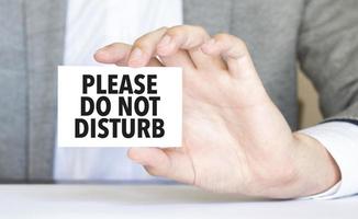 man's hand holding paper sheet with please do not disturb words photo