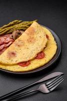 Delicious fresh omelet with cherry tomatoes, bacon, asparagus and spices photo