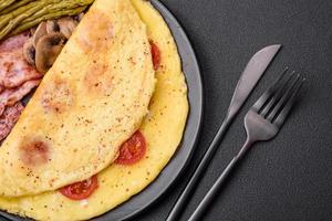 Delicious fresh omelet with cherry tomatoes, bacon, asparagus and spices photo