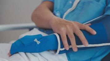 Mens met gebroken arm in gips aan het liegen Aan bed in ziekenhuis. de noodgeval centrum behandeling is gips en blijft hangen met draagdoek voor een verder genezen in een orthopedische kliniek. geduldig pijn van ongeluk blessure. video