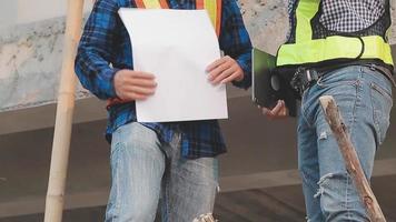 deux hommes d'affaires ingénieur de chantier. objets d'ingénierie sur le lieu de travail avec des partenaires interagissant en arrière-plan video