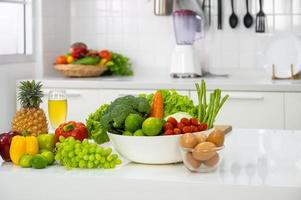 Fresh vegetables, fruits and eggs on white table in home modern kitchen photo