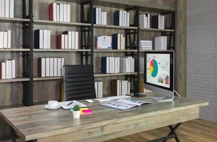 Workspace with desktop computer on wooden desk and black chair with bookshelf on the background photo