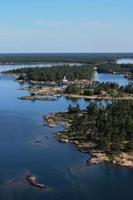 A tiny lighthouse perched on the rocks among the islands of the bay photo