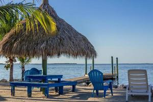 Beach chairs and tiki hut on the shore at King's Kamp, Key Largo, Florida photo