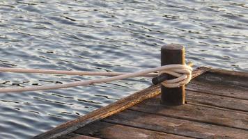 rope tied to a post on a wooden dock at the lake photo