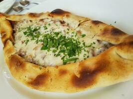 Traditional Turkish Cuisine Kasarli Pide boat-shaped flatbread with cheese, spices and herbs photo