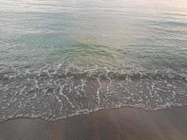 ola del mar en la playa de arena foto