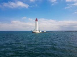 Seascape Sea with lighthouse, calm water and white clouds photo