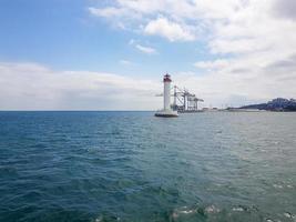 Seascape Sea with lighthouse, calm water and white clouds photo