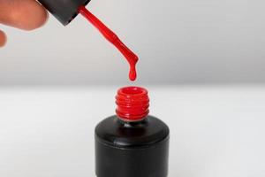 botella con un soltar cerca arriba gel polaco para manicura y pedicure en rojo color. botella con rojo gel polaco foto