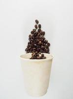 Roasted Arabica coffee beans, ready to make coffee that people like to drink. Placed in a white coffee cup paper on the background. Looks beautiful and appetizing. Drink. photo