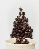 Roasted Arabica coffee beans, ready to make coffee that people like to drink. Placed in a white coffee cup paper on the background. Looks beautiful and appetizing. Drink. photo