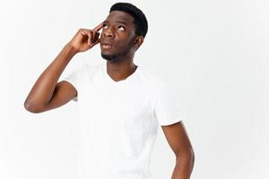 interested young man of african appearance in white t-shirt touches his head with his hand photo