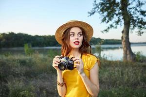 mujer fotógrafo en sombrero rojo labios mira hacia naturaleza Fresco aire foto
